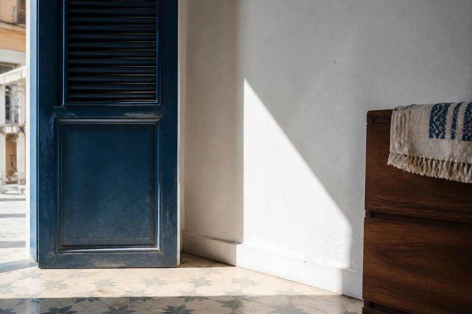 Lumière naturelle sur une menuiserie indigo et un mur blanc dans un intérieur dakarois.